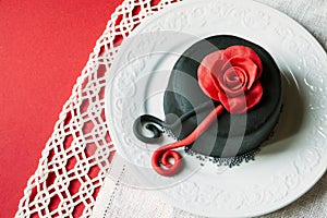 Romantic cake on a plate with decorations. Rose above. Red background