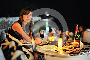 Romantic candlelit dinner by the sea at night. Beautiful young girl at the table