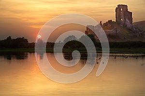 Romantic castle ruins, sunset and lake