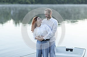 Romantic Caucasian man hugs Latin woman, couple enjoys time standing in boat, sailing in