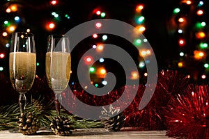 Romantic Christmas and New Year dinner of a couple in love with two glasses of champagne. Red tinsel and spruce branch with a cone