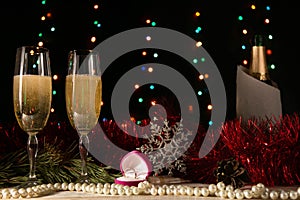 Romantic Christmas and New Year dinner of a couple in love with two glasses of champagne and a wedding ring. Red tinsel and spruce