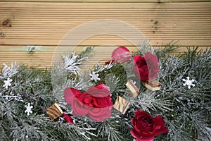 Romantic christmas photography image with fresh red roses and luxury chocolates laid on snow garland with natural wood background