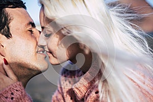 Romantic close up portrait of yong people kissing and enjoying love together - blonde caucasian girl and handsome boy with. closed