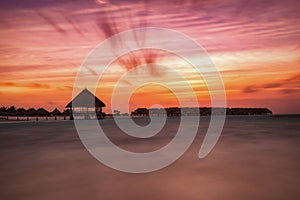 Romantic, colorful sunset over water lodges in the Maldives