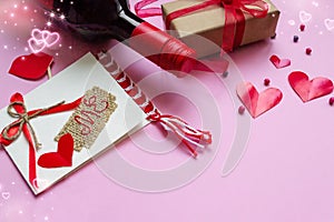 Romantic composition for valentine`s day. A bottle of red wine, a gift, a card with the inscription love me. Place for text, pink