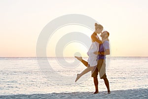 Romantic couple on the beach at colorful sunset