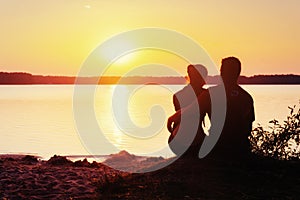 Romantic couple on the beach at colorful sunset background