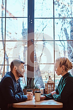 Romantic couple in the cafe is drinking coffee and talking.