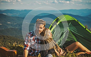 Romantic couple camping outdoors and sitting near tent. Happy Man and woman on a romantic camping vacation. Young couple