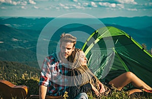 Romantic couple camping outdoors and sitting near tent. Happy Man and woman on a romantic camping vacation. Young couple