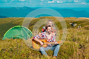 Romantic couple camping on spring landscape. Adventure for young lovers campers on nature, man with guitar.