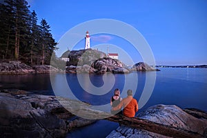 Romantic couple on cliff by ocean looking at  Lighthouse.