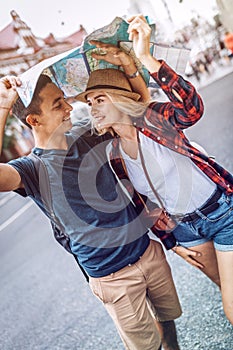 Romantic couple covering head with map