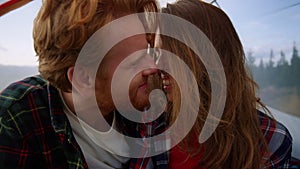 Romantic couple cuddling together in tent. Smiling woman and man touching noses