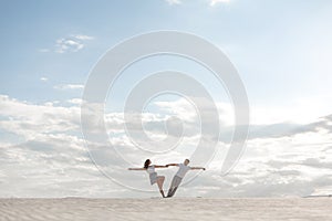 Romantic couple dancing in sand desert. The guy lifts the girl above himself. Sunset sky