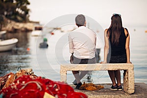 Romantic couple on a date in nature,sitting on the bench looking at serene ocean scene.People living on the coast lifestyle