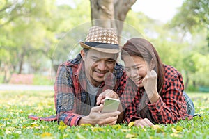 Romantic couple dating in the park. lovers lying on the lawn looking at mobile phone together