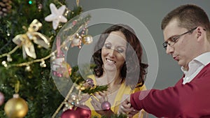 Romantic couple decorating Christmas tree, enjoying mutual pastime at home