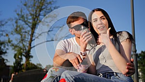 Romantic couple drink coffee and sit on the green grass in the park. Couple trust, love and happiness concept. Medium