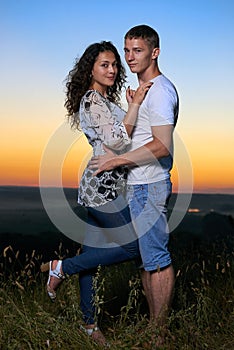 Romantic couple embrace at sunset, beautiful landscape and bright yellow sky, love tenderness concept, young adult people