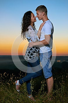 Romantic couple embrace at sunset, beautiful landscape and bright yellow sky, love tenderness concept, young adult people