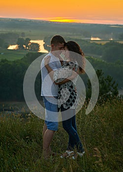 Romantic couple embrace at sunset on outdoor, beautiful landscape and bright yellow sky, love tenderness concept, young adult