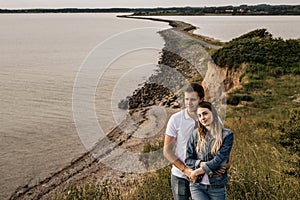 Romantic couple in embrance stand on the beach with mountains