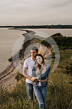 Romantic couple in embrance stand on the beach with mountains