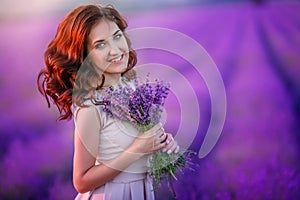 Romantic couple in an endless lavender field at sunset. blond Man and red-haired girl with a bouquet of flowers in love