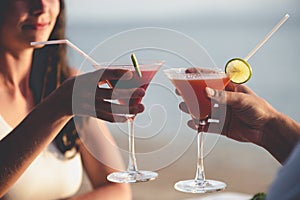 Romantic couple enjoy sunset in restaurant on the beach drinking cocktails