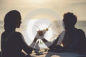 Romantic couple enjoy sunset in restaurant on the beach drinking cocktails