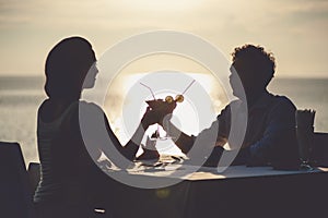 Romantic couple enjoy sunset in restaurant on the beach drinking cocktails