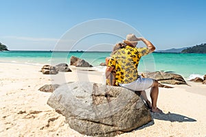 Romantic Couple Enjoying Beautiful seascape, sitting on the rock, on the tropical beach. Travel Vacation, real people Lifestyle