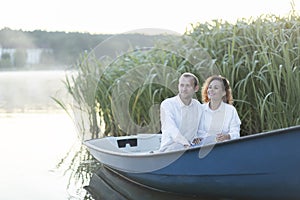 Romantic couple enjoys time sitting in boat, sailing in water. Happy smiling Caucasian man