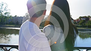 Romantic couple in a green summer park near the pond. A man touches girlfriend`s face, enjoying her beloved, love. Happy