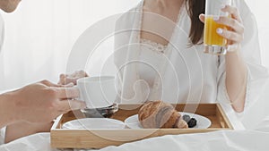 Romantic Couple Having Breakfast And Holding Hands While Relaxing In Bed Together