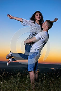 Romantic couple having fun at sunset on outdoor, beautiful landscape and bright yellow sky, love tenderness concept, young adult