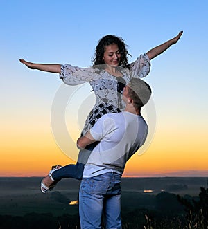 Romantic couple having fun at sunset on outdoor, beautiful landscape and bright yellow sky, love tenderness concept, young adult