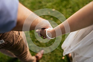 Romantic couple holding hands standing on green grass