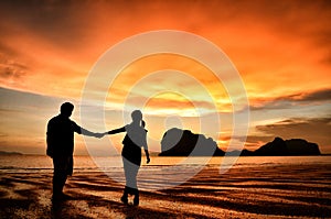 Romantic couple holding hands at sunset on beach