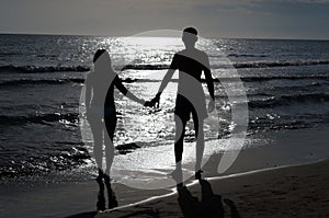 Romantic couple holding hands at sunset on the beach