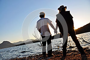 Romantic couple holding hands sunset edge of lake