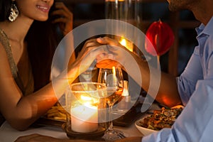 Romantic couple holding hands together over candlelight photo