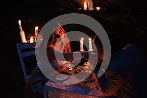 Romantic couple holding hands together over candlelight during romantic dinner outdoors.