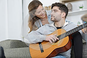 romantic couple at home man plays guitar