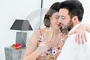 Romantic couple in hotel room with sparkling wine.