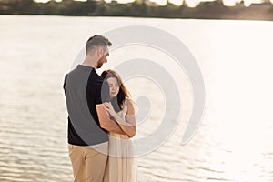 Romantic couple is hugging outdoors. elegant and stylish woman and man in love are walking along the lake. Happy moments together
