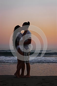 Romantic couple kissing on beach at sunset.