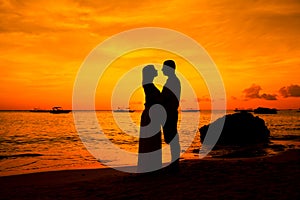 Romantic couple kissing at beach with sunset in the bac